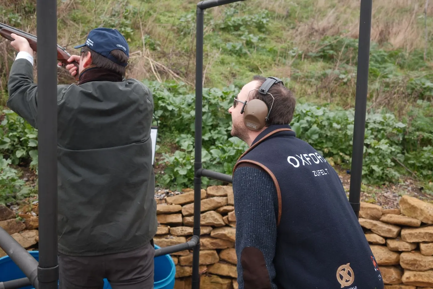 A member coaching a shooter at the stand, wearing an Oxford vest