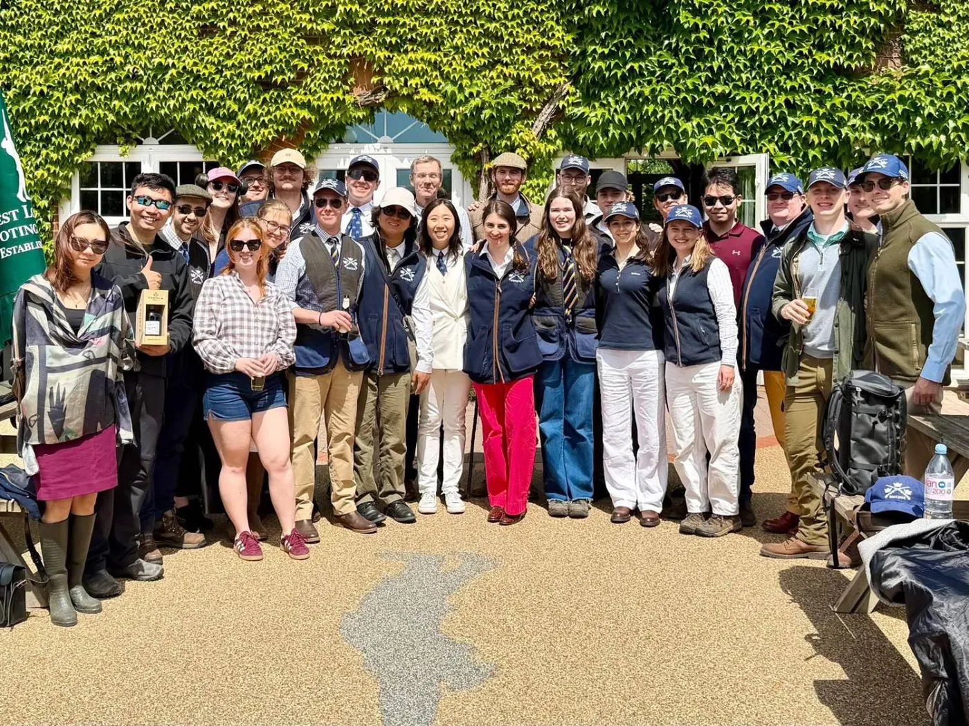 A large group of members in front of an ivy-covered clubhouse