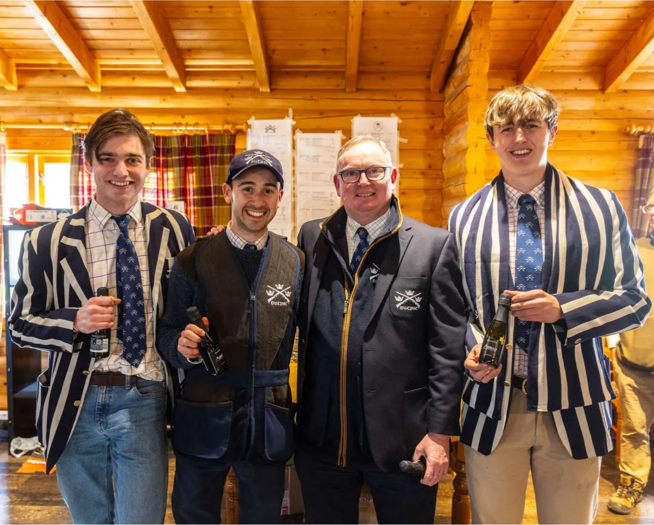 Four members with prizes in a log-cabin clubhouse