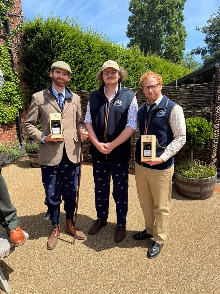 Three members holding prize bottles of port